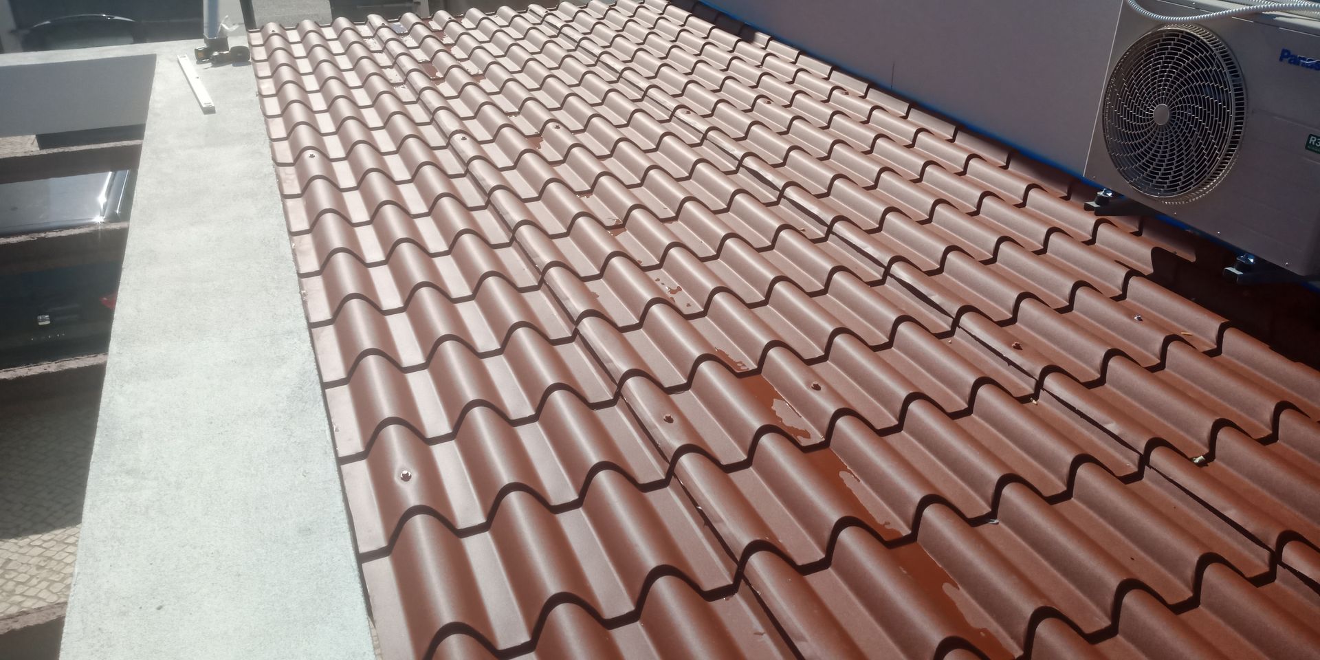 Telhado de telhas marrons com aparelho de ar condicionado.