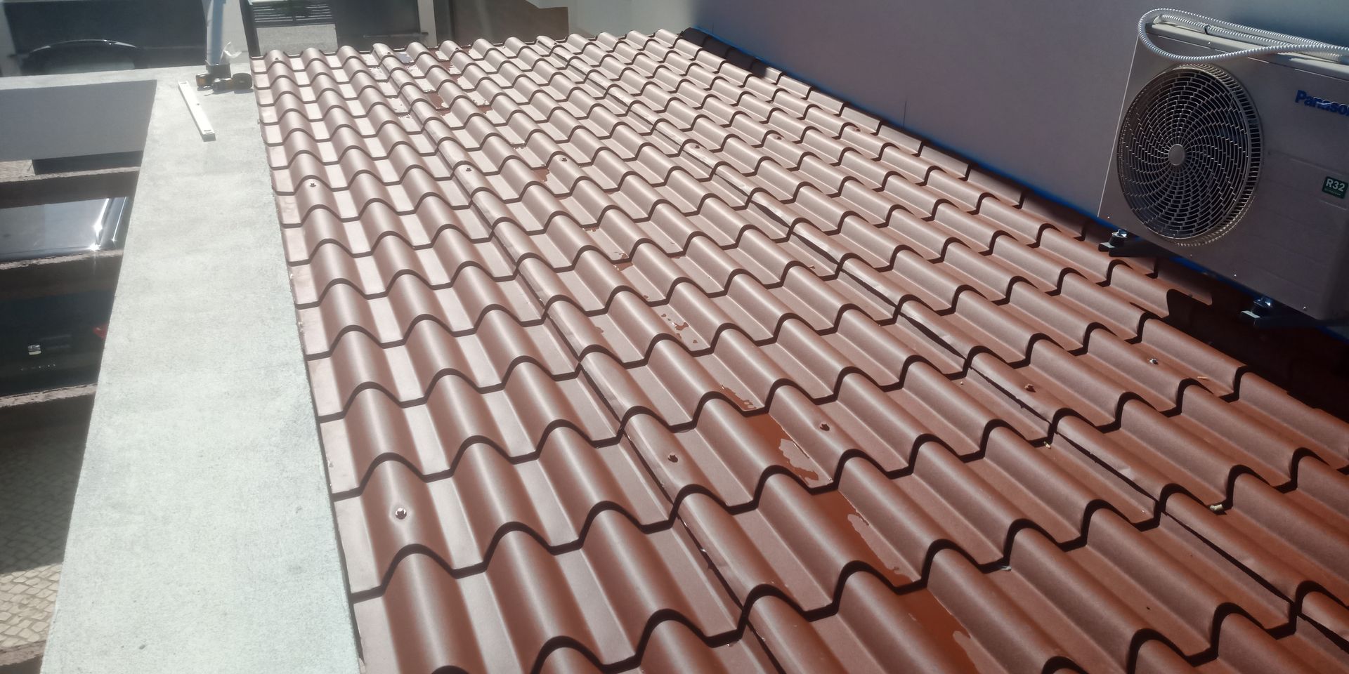 Telhado de telha marrom com unidade de ar condicionado em um prédio.