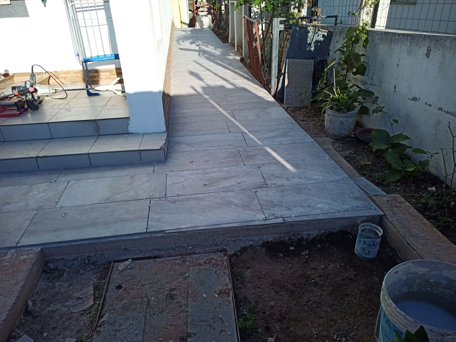 Caminho de concreto ao lado de um prédio branco com degraus e uma cerca.