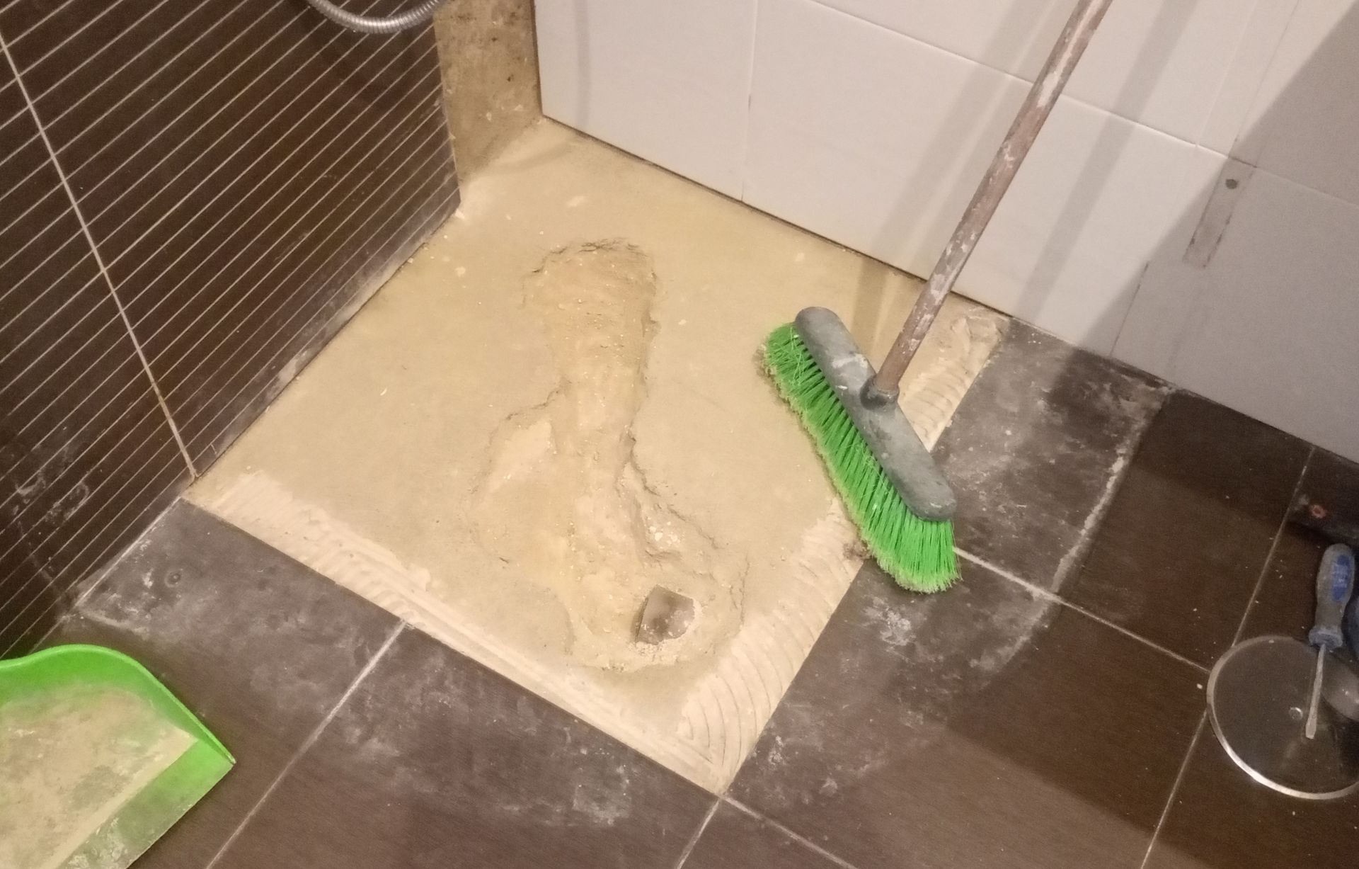 Piso do banheiro com cimento fresco, rejunte e produtos de limpeza.