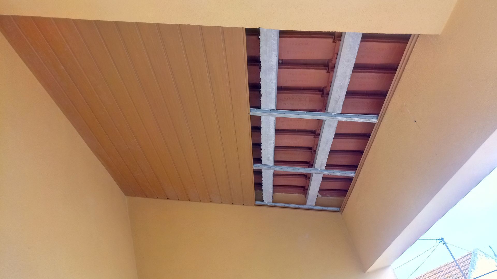 Forro de madeira parcialmente instalado, expondo a estrutura do telhado acima.