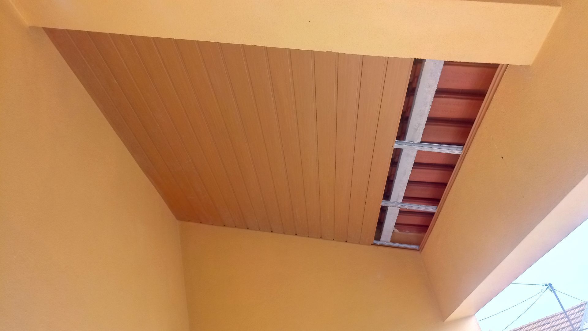 Teto laranja com tijolos e vigas aparentes.