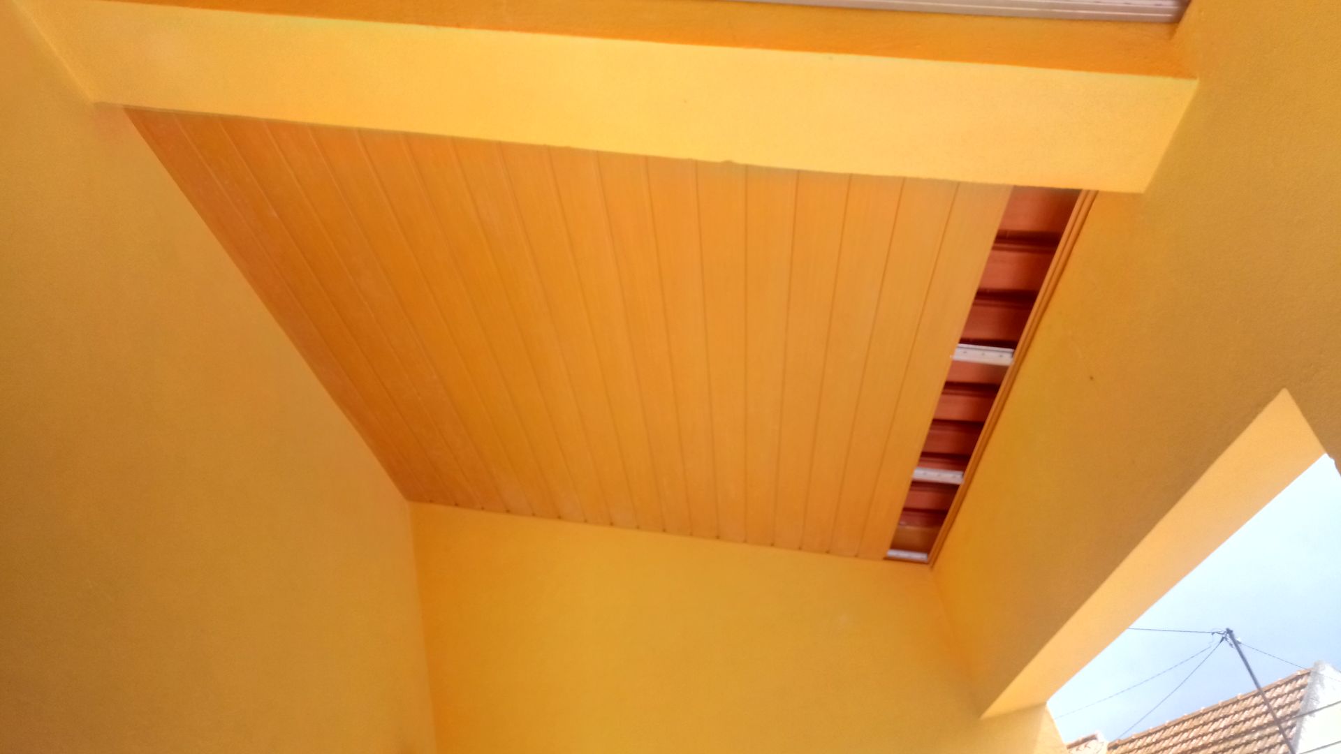 Interior amarelo com teto de painéis de madeira.