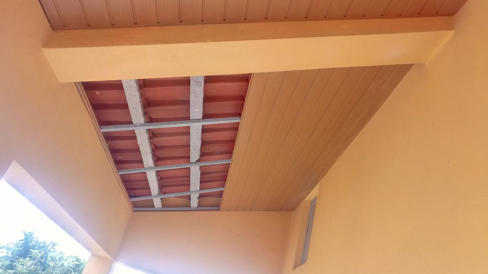 Teto bege com estrutura metálica aparente, azulejos vermelhos e paredes pintadas na mesma cor.