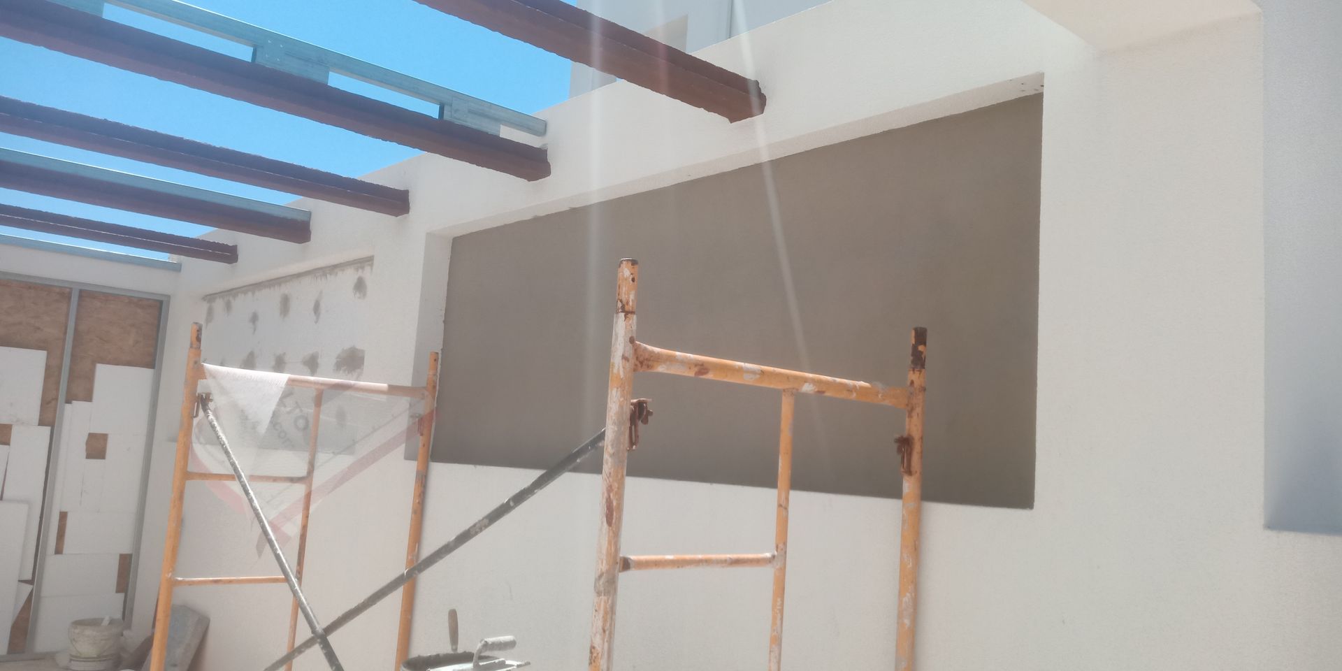 Canteiro de obras com andaimes e uma grande janela, sob o céu.