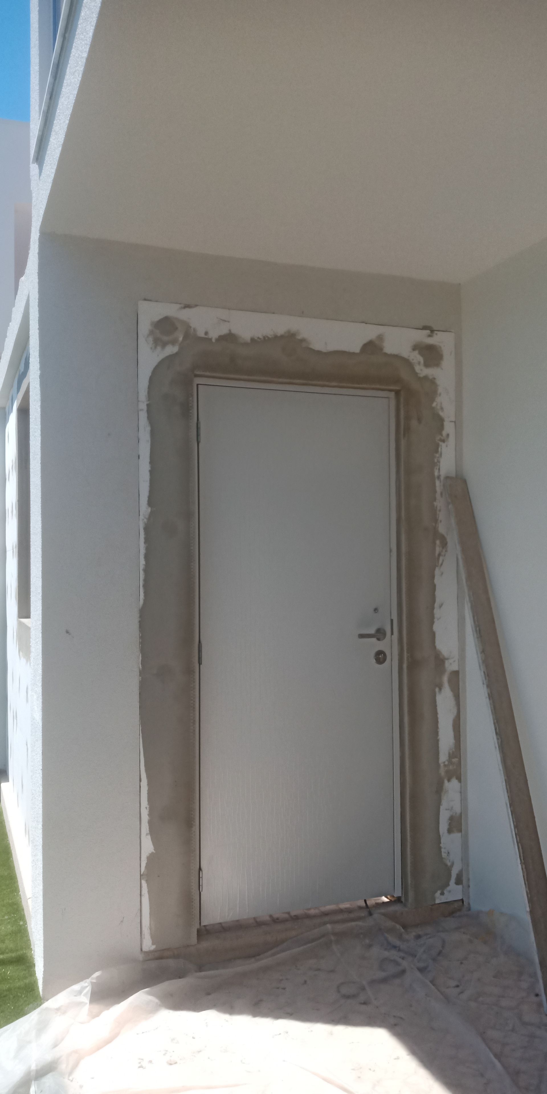 Porta branca em uma entrada, cercada por estuque fresco.