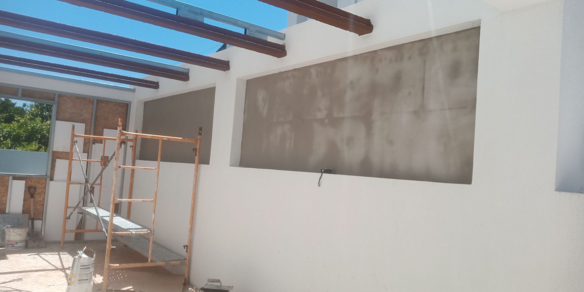 Canteiro de obras com estrutura parcialmente construída; andaimes e paredes expostas.