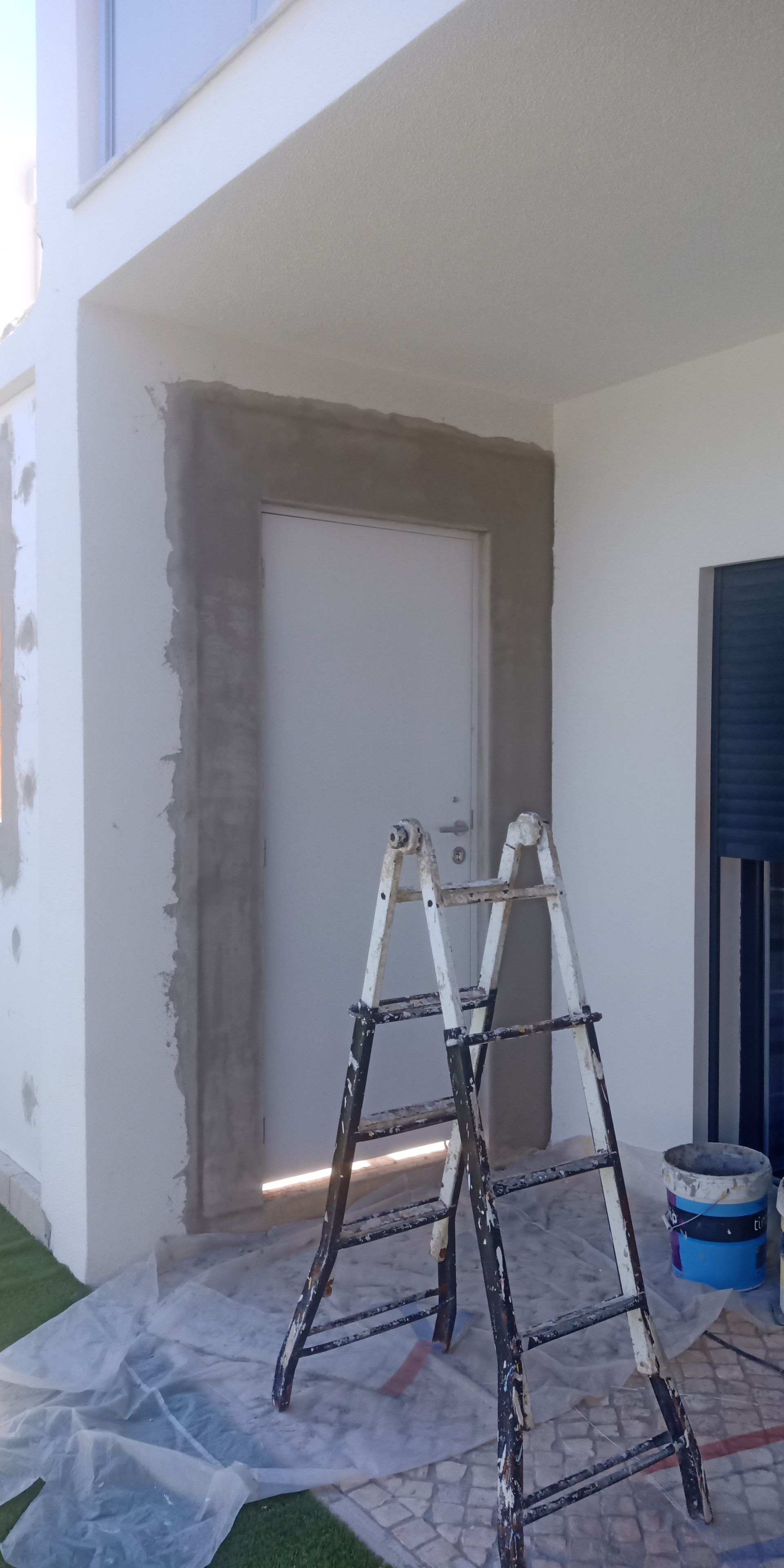 Canteiro de obras: uma moldura de porta em reforma, escadas e lonas.