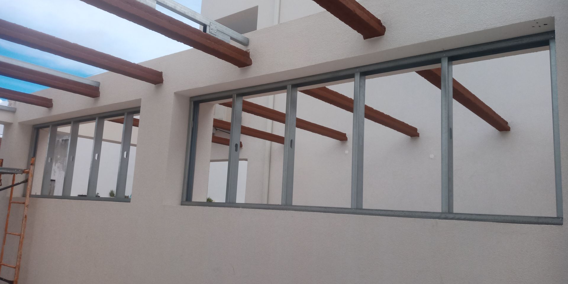 Vista exterior de um edifício com várias janelas de vidro e vigas de madeira.