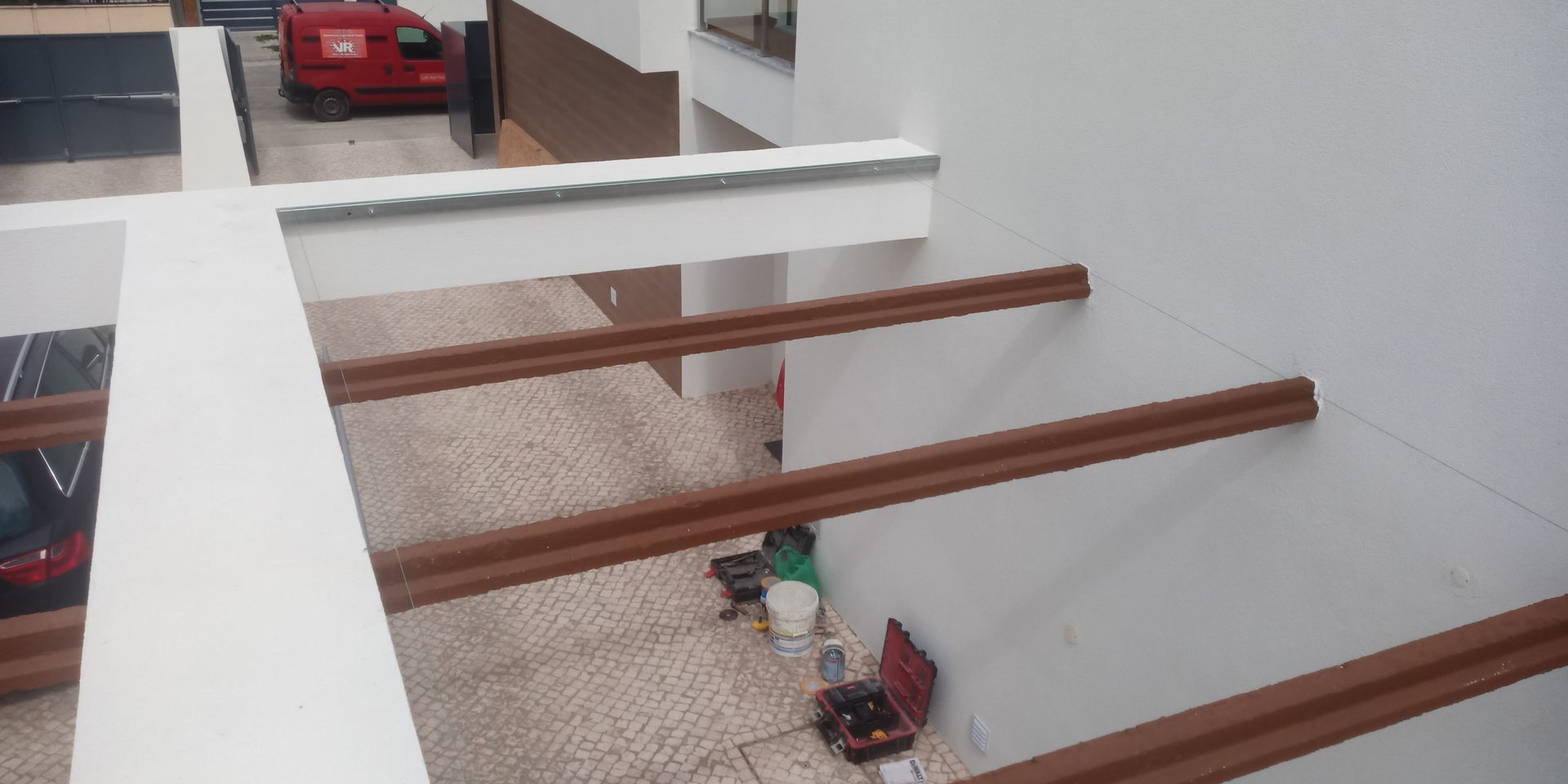 Vista de um ângulo superior do interior de um edifício com um carro vermelho ao fundo e vigas castanhas.