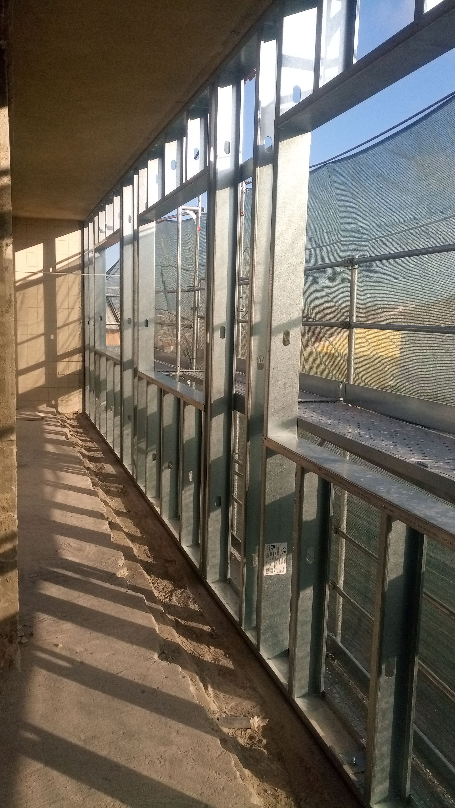 Estrutura metálica para uma varanda com vista para o espaço exterior e tela de malha.