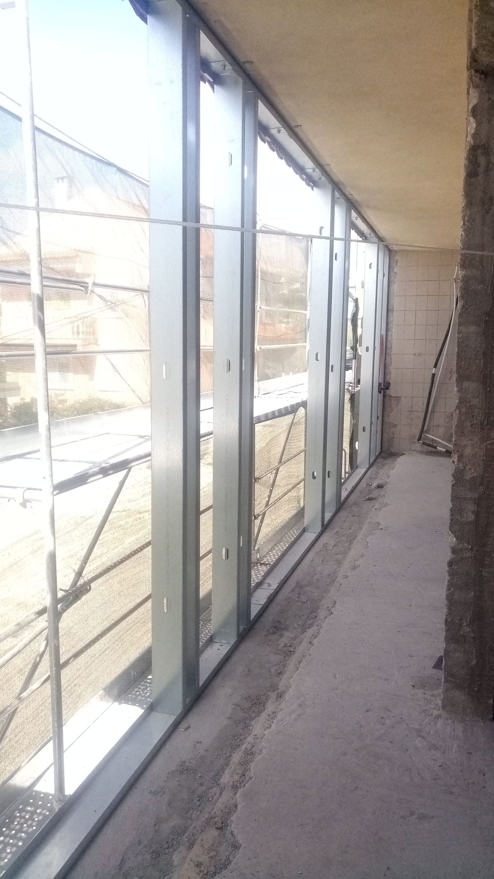 Vista interna do canteiro de obras. Caixilhos de metal para janelas já instalados, com paredes de concreto inacabadas.