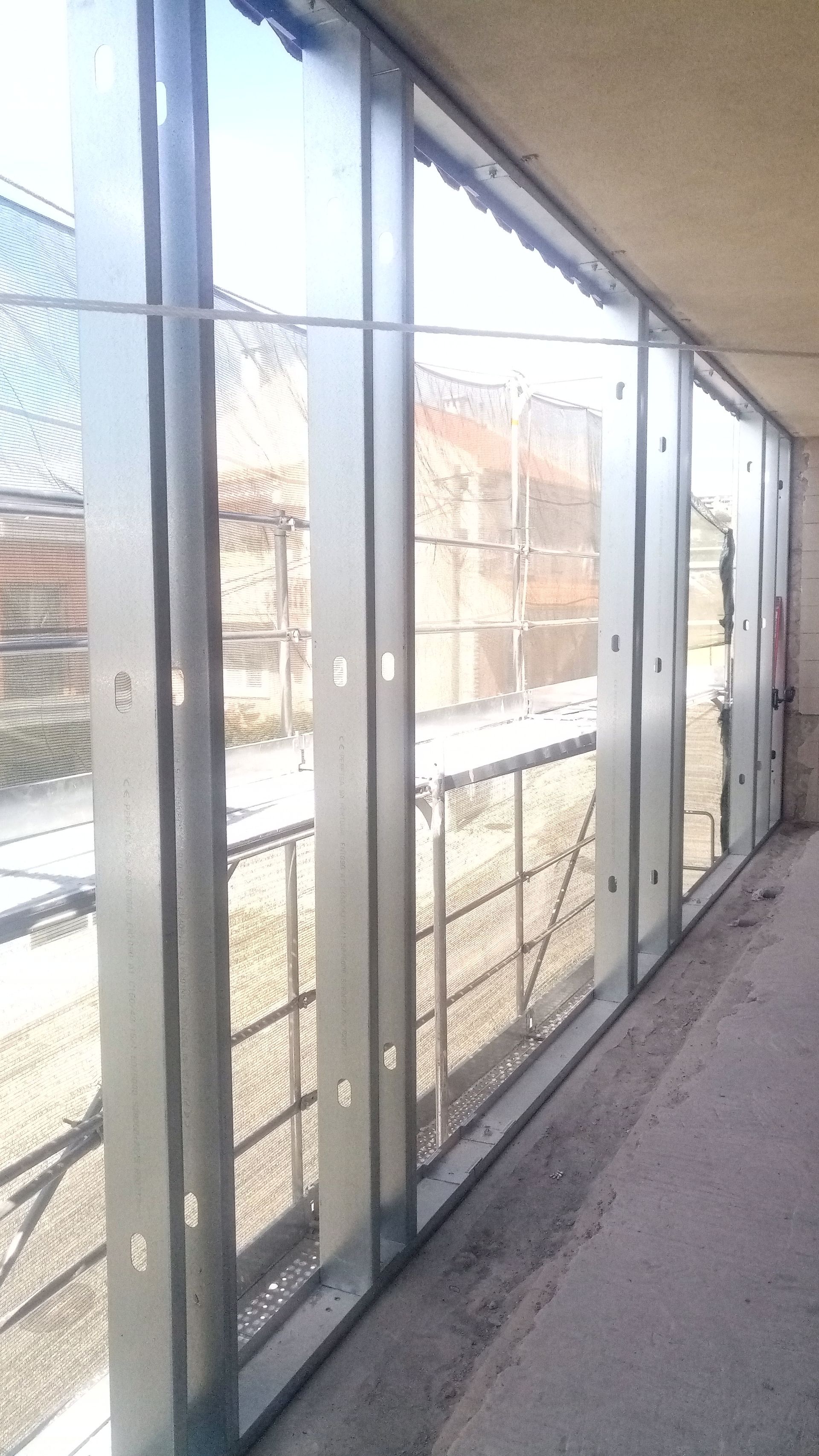 Estrutura metálica de janelas em um prédio em construção, com vista para o exterior.