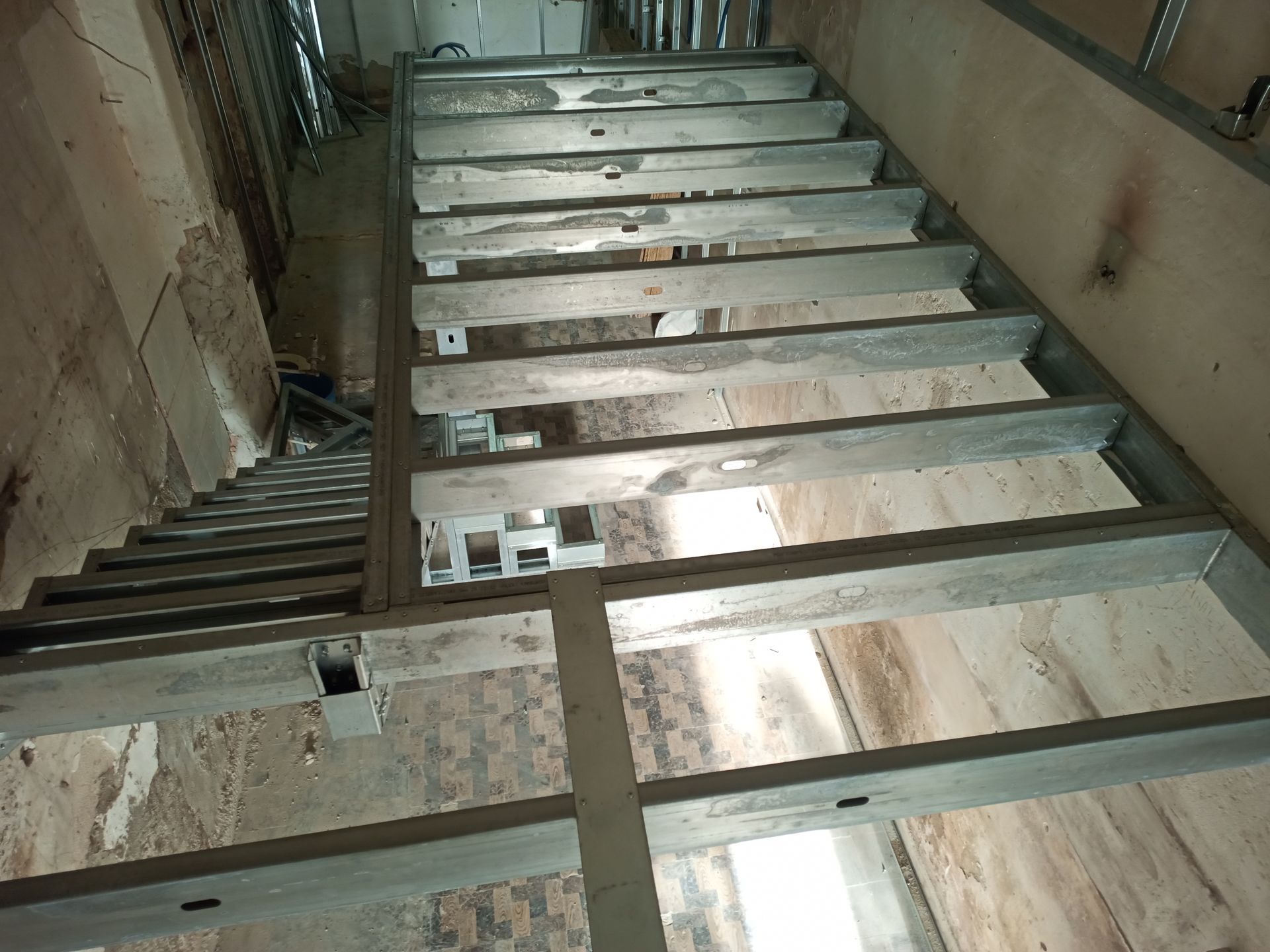 Escada metálica que leva ao andar superior, situada em um interior estreito e antigo.