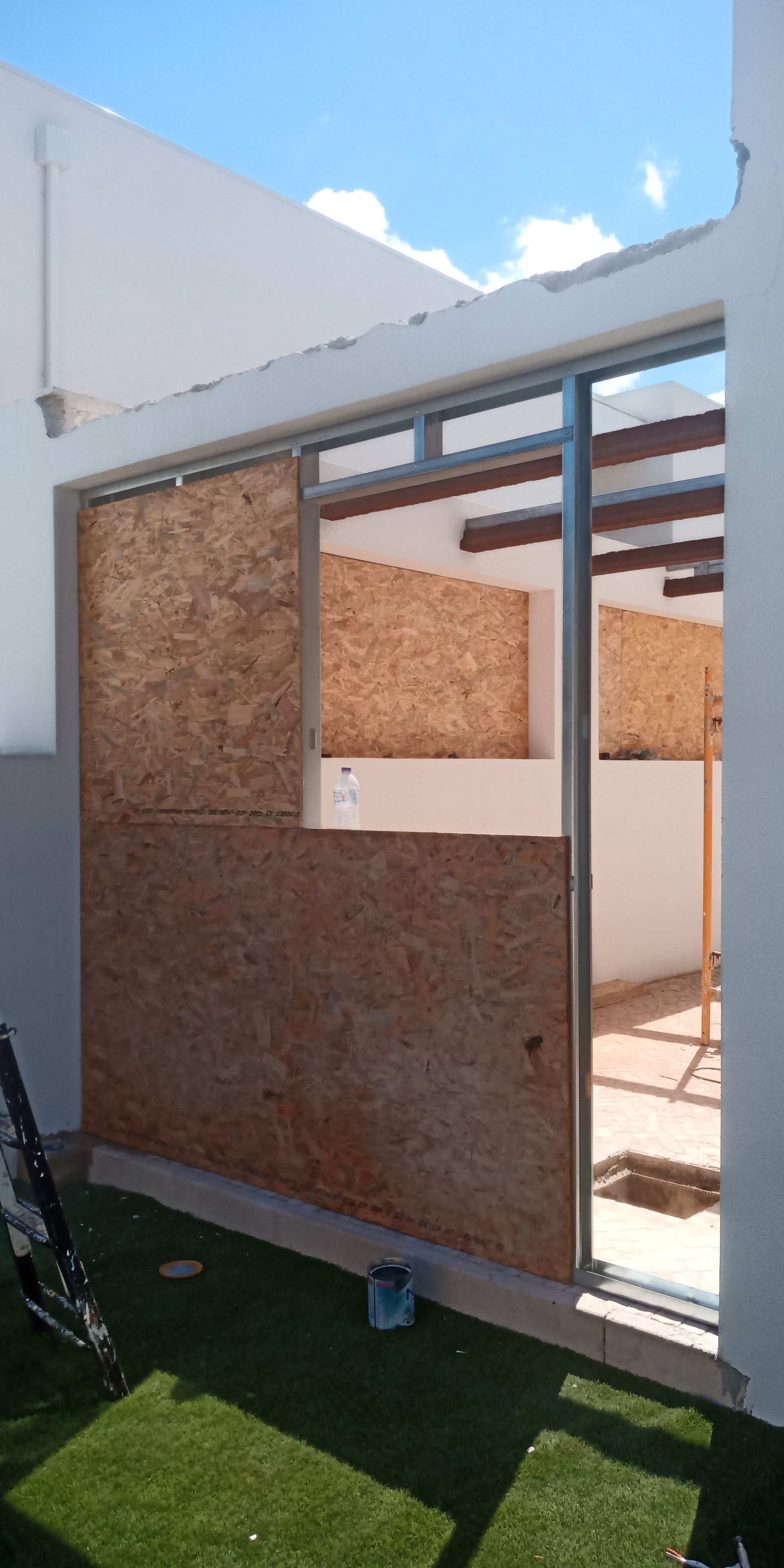 Construção em andamento: Revestimento em placa OSB e estrutura metálica para uma porta de correr de vidro.