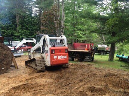 A bobcat bulldozer is driving through a dirt field.
