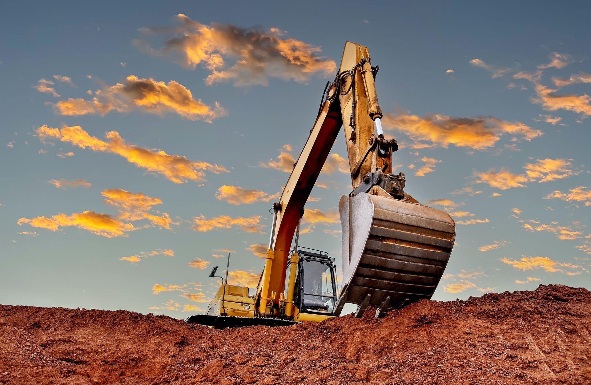 A yellow excavator is digging a hole in the dirt.