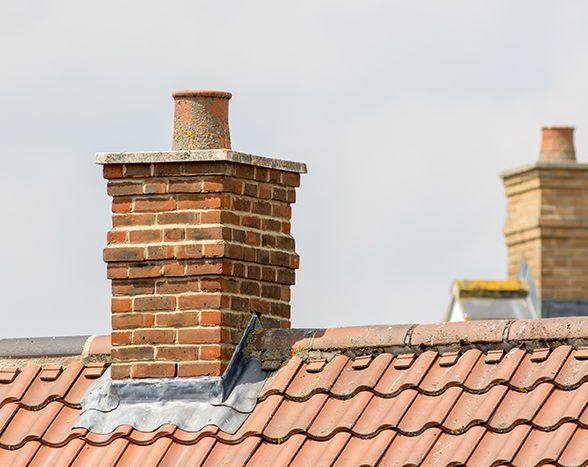 a brick chimney on top of a tiled roof .