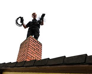 a man is standing on top of a brick chimney .