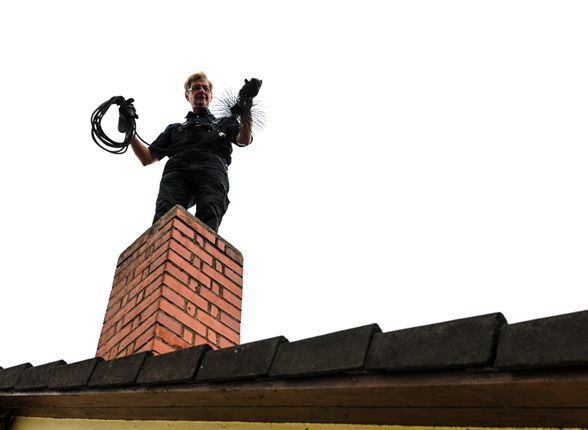 a man is standing on top of a brick chimney holding a brush