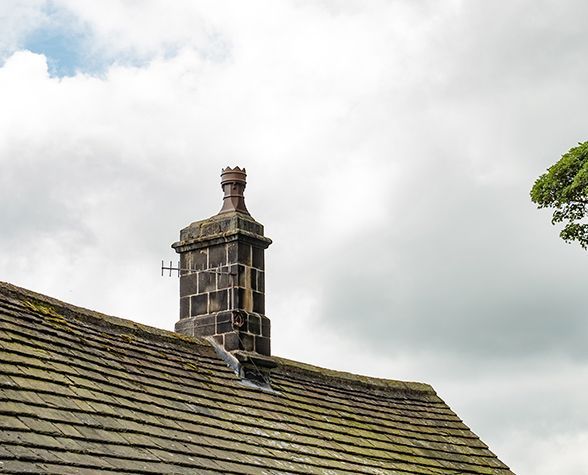 a chimney on top of a roof with a tree in the background .