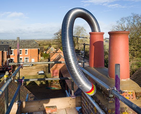 a stainless steel hose is attached to a brick chimney