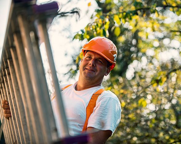 a man wearing a hard hat is standing on a ladder .