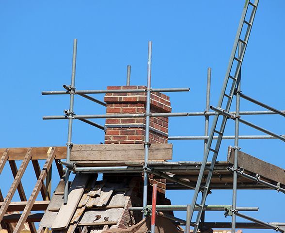 a brick chimney is sitting on top of a scaffolding structure .