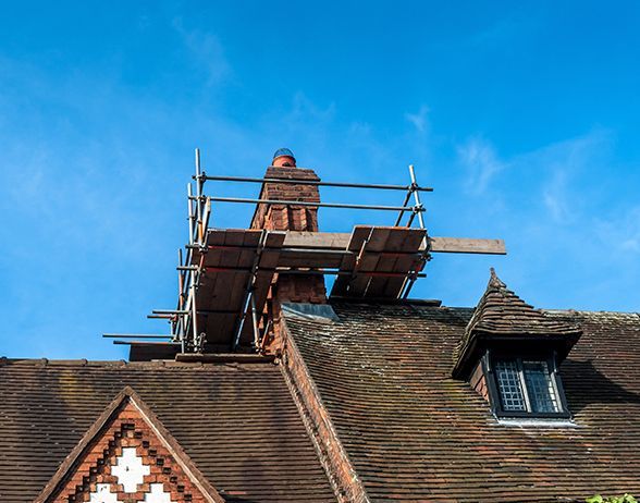 a chimney is being repaired on the roof of a house .