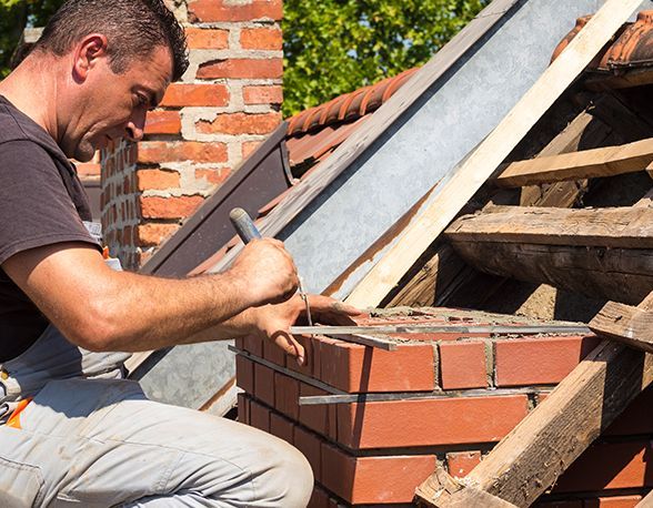a man is working on a brick chimney on a roof .