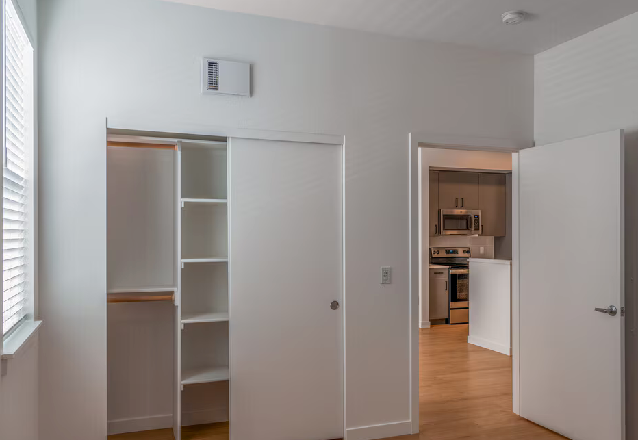 Photo of a bedroom with a high ceiling and a closet with a built-in shelf