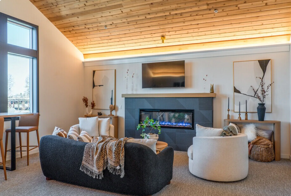 Photo of a unique living room, with a fireplace, tall windows for plenty of natural light, a vaulted ceiling and open space