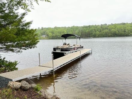A pontoon boat is docked at a dock on a lake