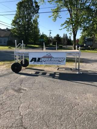 A white sign on wheels is sitting on the side of a road.