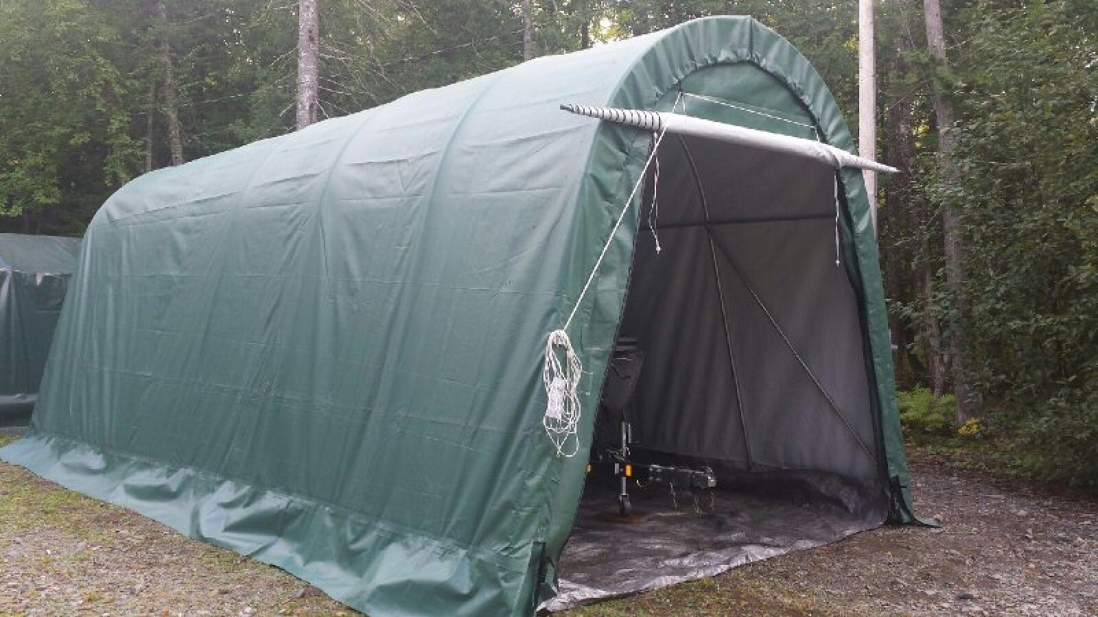 A green garage is sitting in the middle of a dirt field.
