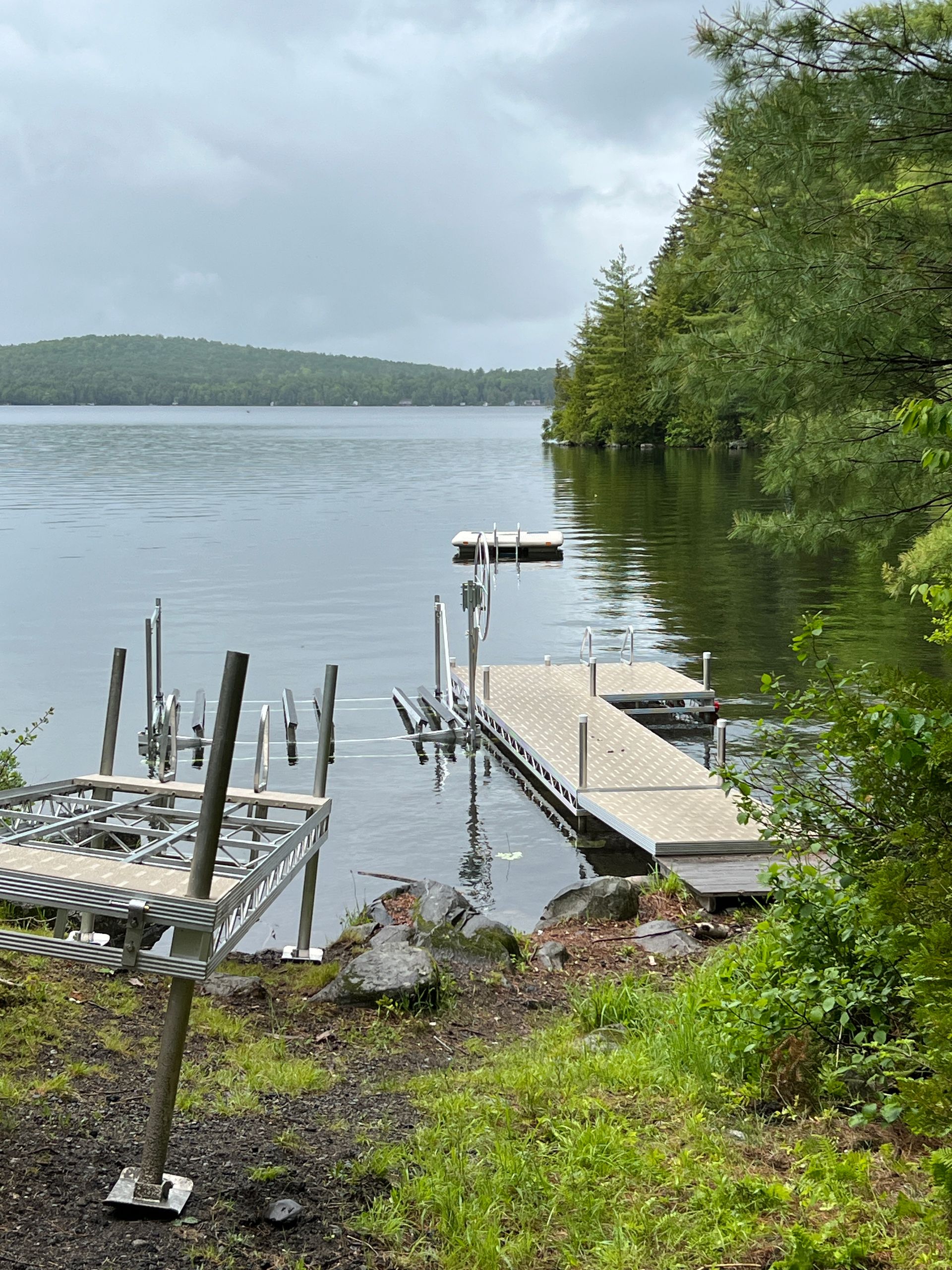 A dock on the shore of a lake with trees in the background.