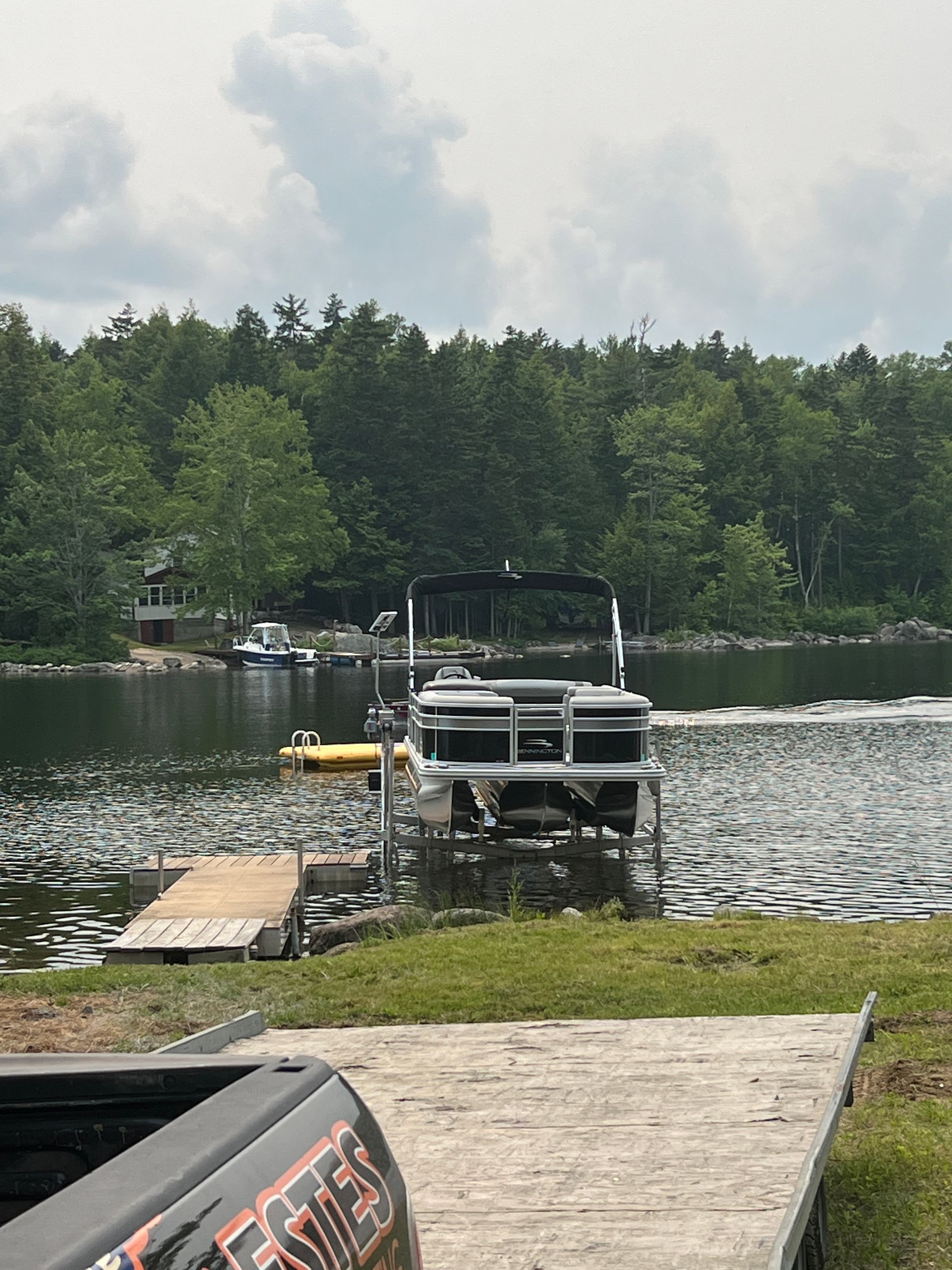 A pontoon boat is docked at a dock on a lake