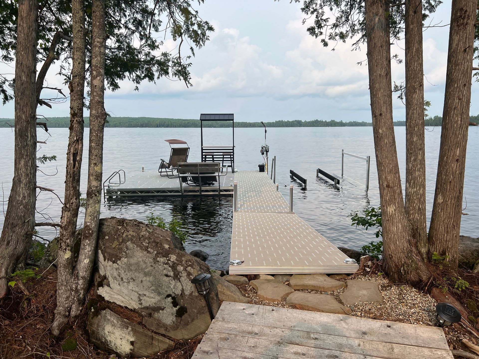 a dock in the middle of a lake surrounded by trees