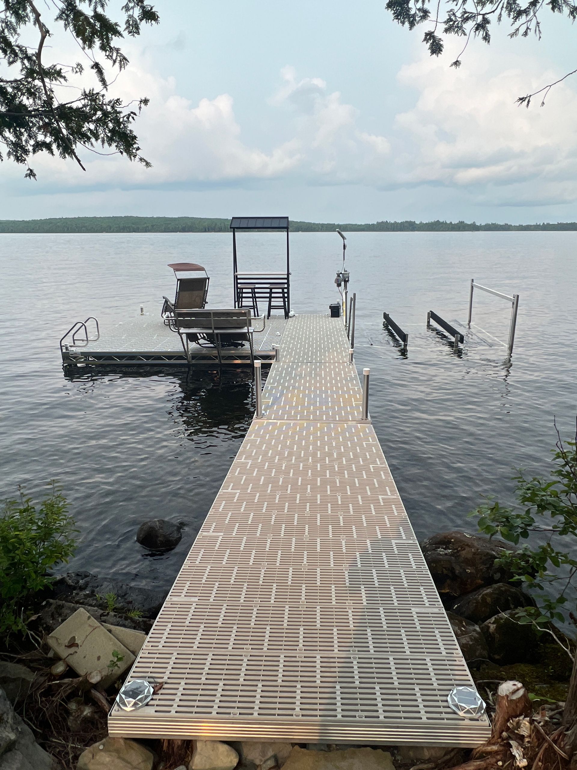 A dock leading to a lake with a boat on it