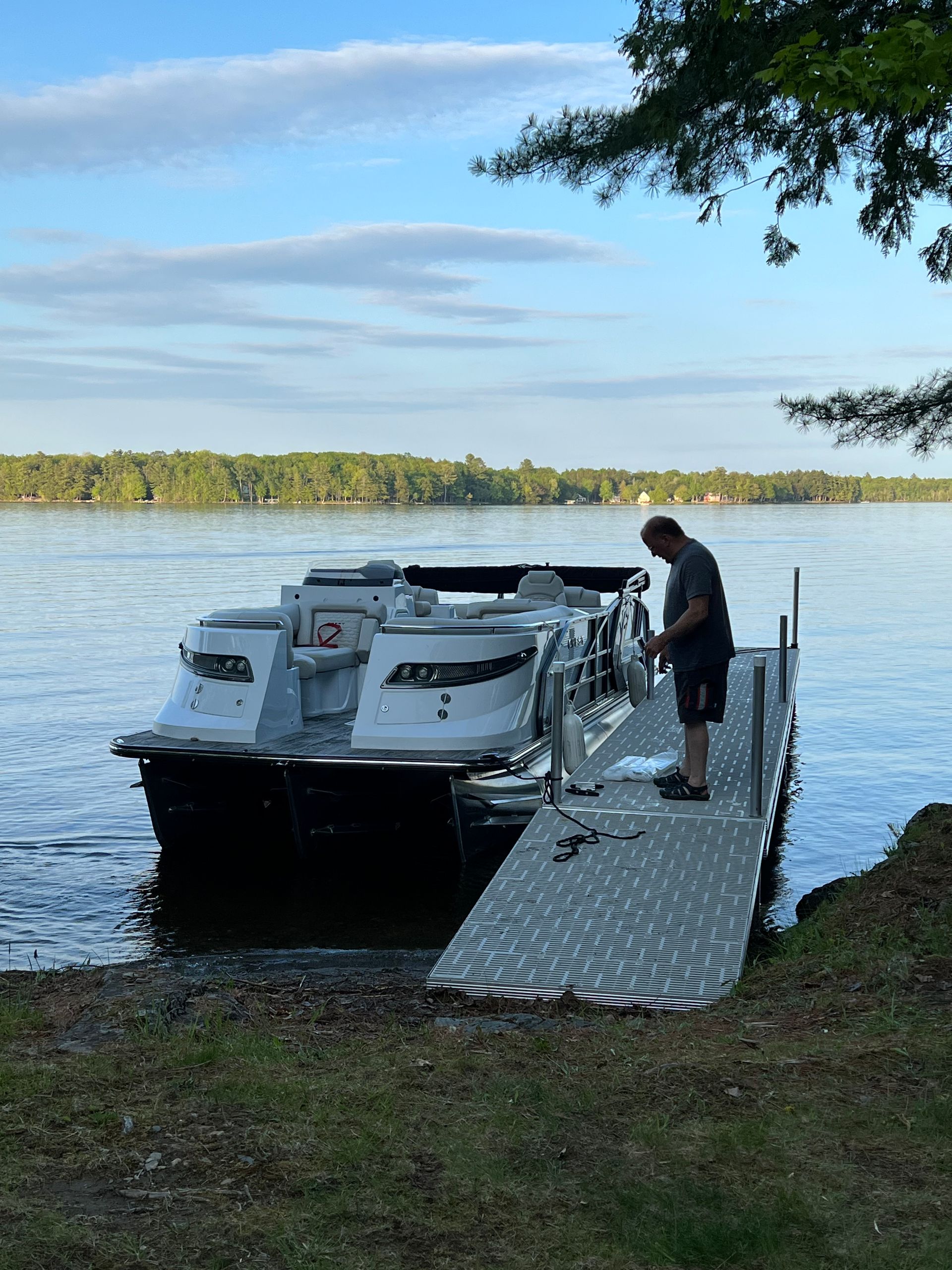 A man is standing on a dock next to a boat in the water.