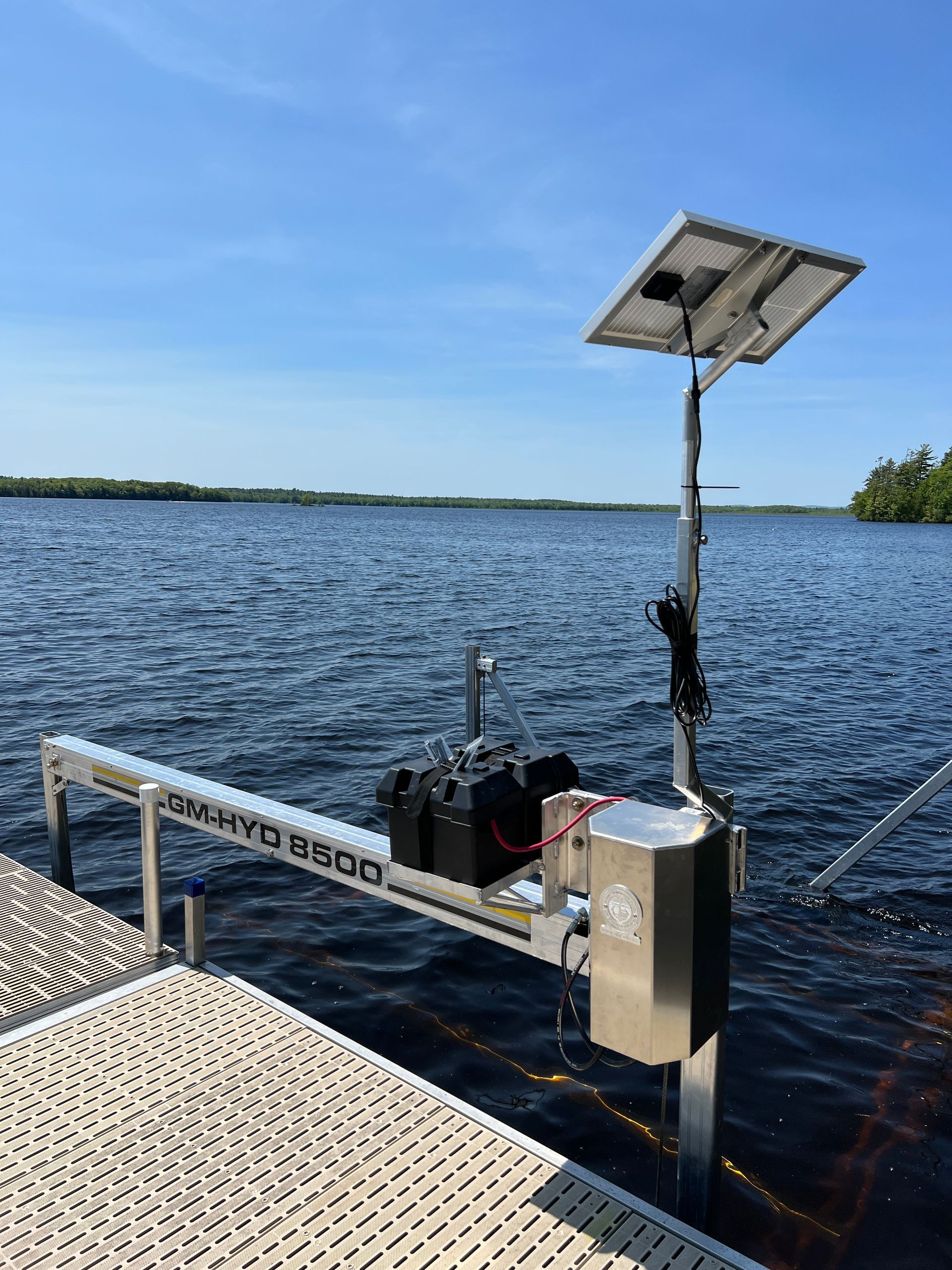 A dock with a solar panel on top of it next to a lake.