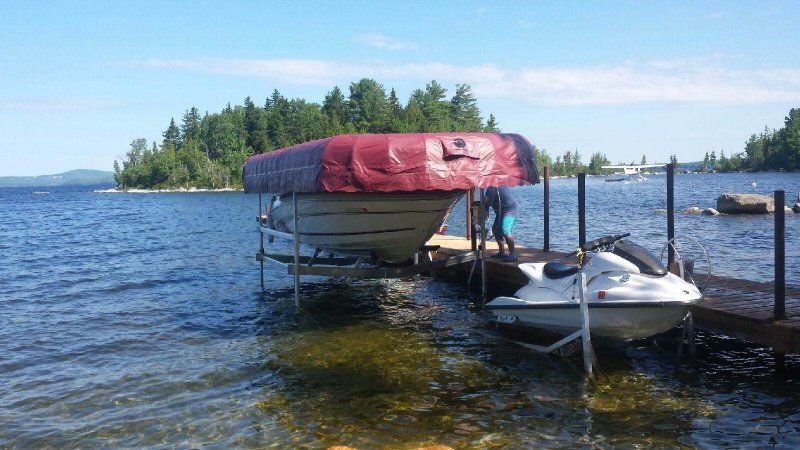 A boat is sitting on a dock next to a jet ski.