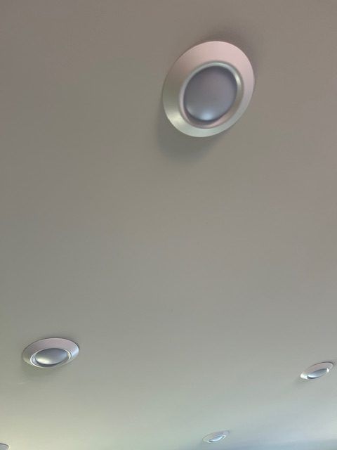 Several circular, flush-mounted recessed ceiling lights with silver trim set against a plain, light-colored ceiling.
