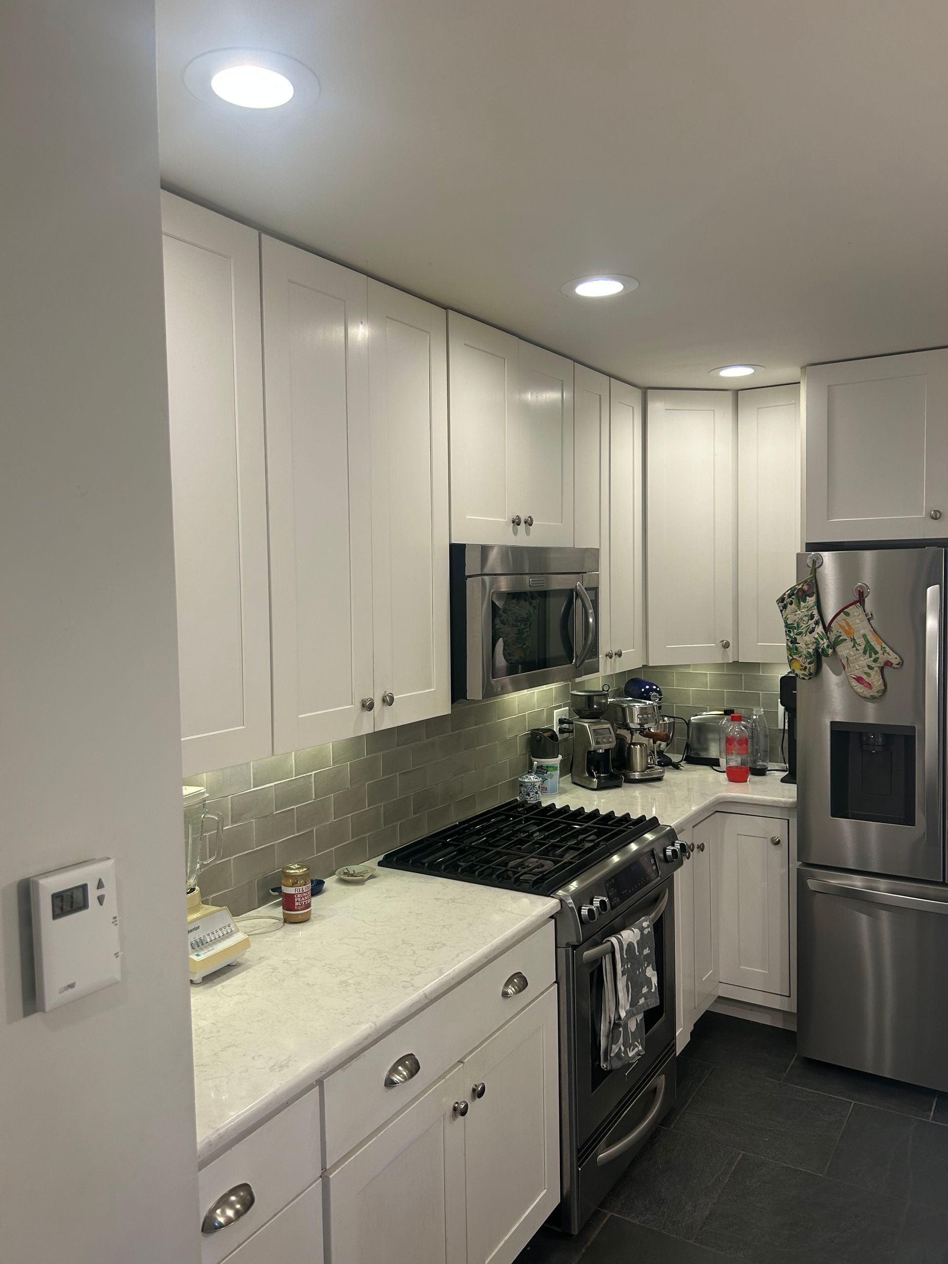 A hand holds a trowel, applying textured gray plaster or cement onto a wall surface.