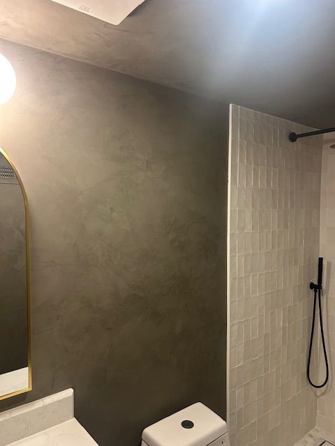 A mattress on a wooden pallet frame placed on a raised platform against a rustic, distressed plaster wall.