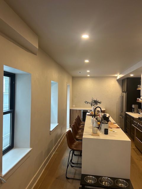 A modern fireplace with a linear black insert set into a smooth, light beige concrete-style wall below a wooden mantel.