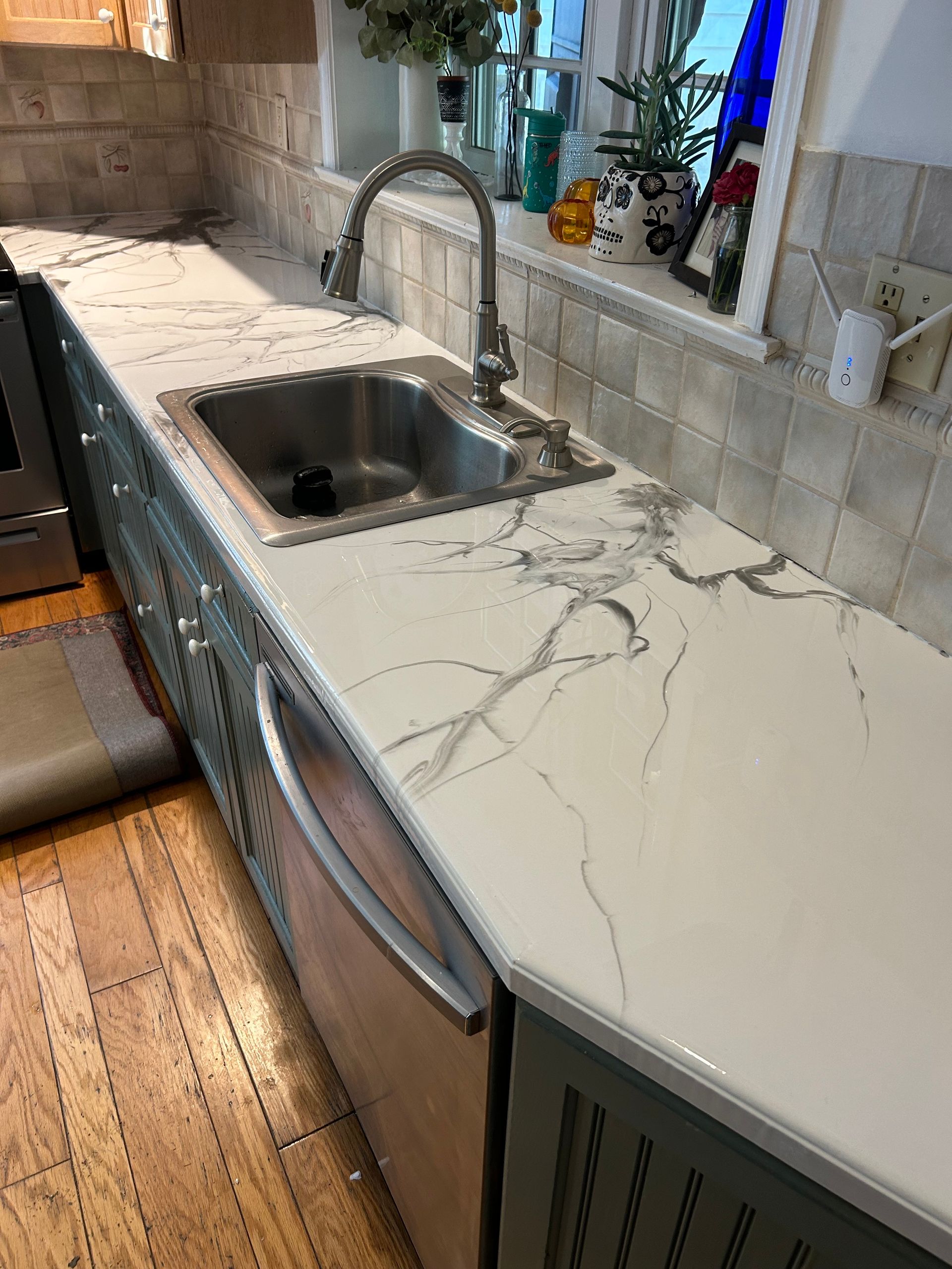 Modern white kitchen island with marble-look countertop, gold faucet, and built-in stovetop in a bright, white kitchen.