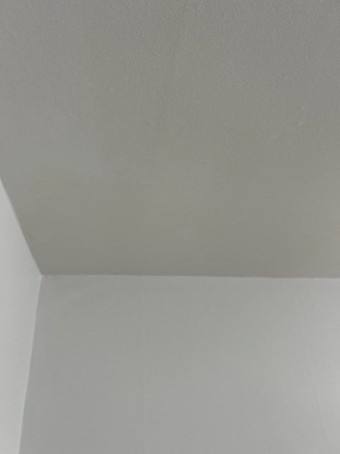 An interior room under construction with unfinished drywall, white ceilings, recessed lighting, and patio doors.