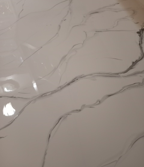 A close-up of white marble surface with flowing grey vein patterns.