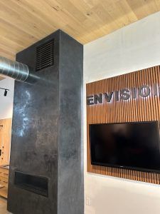 A charcoal-colored fireplace structure next to a wall with wood slats featuring the word 